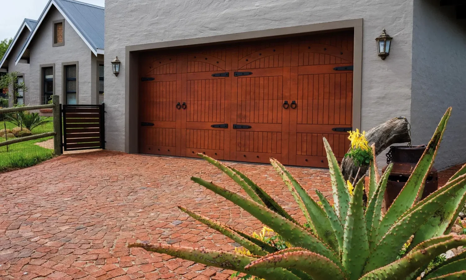Solid timber garage door with wrought-iron strap hinges on a face-brick home